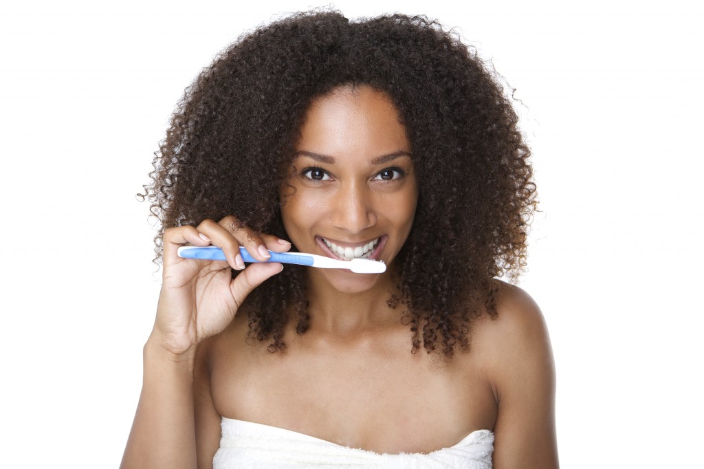 Beautiful young woman brushing teeth