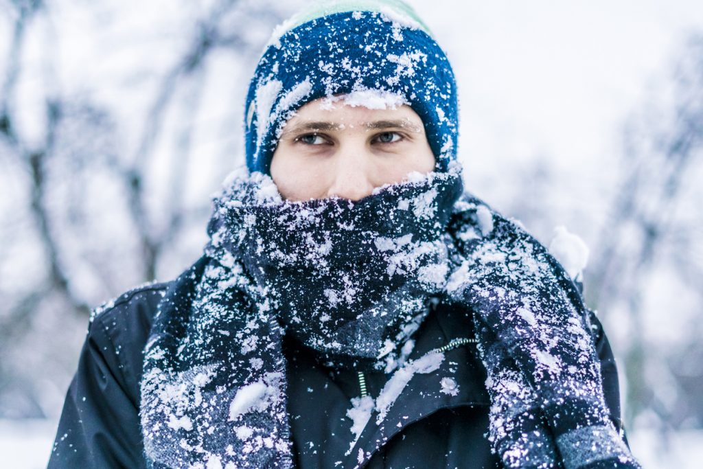 close up of a man's face with scarf covered by snow on a winter day