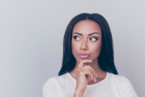 a young woman looking unsure as her finger presses on her chin and her eyes look sideways