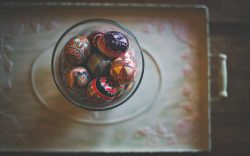 Decorative eggs in a glass bowl on a flowered tray.