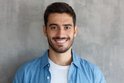 A close up image of a dark-haired man smiling