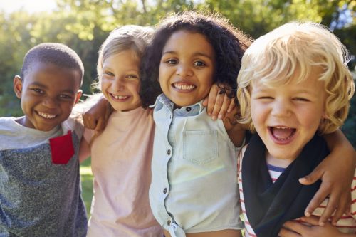 Four children hanging out together in a garden and smiling