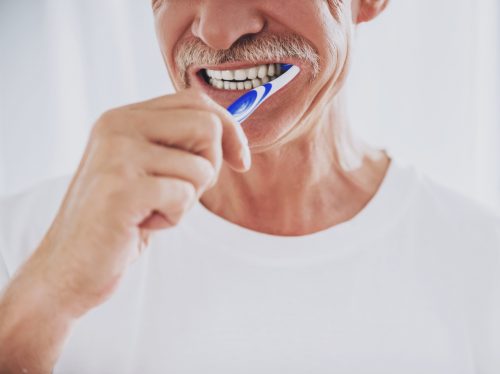 a senior man brushing his teeth in the bathroom