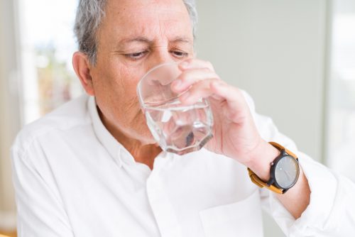 a senior man drinking a glass of water